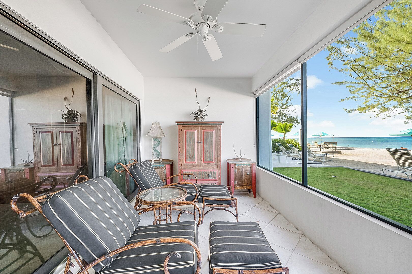 A balcony with wicker furniture, a ceiling fan, and a view of the beach.