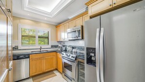 Una cucina moderna con elettrodomestici in acciaio inossidabile, mobili in legno e una finestra con persiane.