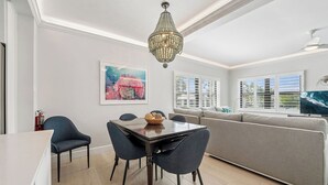 Una sala de estar moderna con comedor, una araña, un sofá y un televisor.
