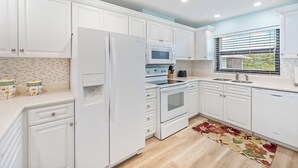 A modern kitchen with white cabinetry, a built-in oven, microwave, and refrigerator. - Casa Caribe #11 - 3 Bed, 3 Bath - Oceanfront, Second Floor (Seven Mile Beach)