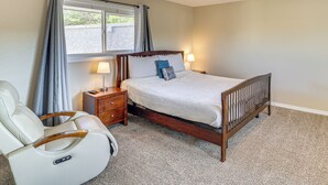 Een slaapkamer met een bed, een massagestoel, een nachtkastje, een lamp en een plafondventilator.