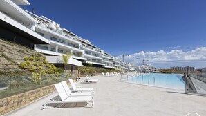 A modern hotel with a rooftop pool, white balconies, and a clear blue sky. - Sonrisa | Sea view - pool - terrace (Estepona)
