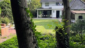 A modern two-story house with a large lawn and a patio area.