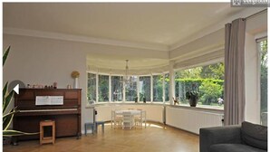 A spacious living room with a piano, a dining table, and a sofa.