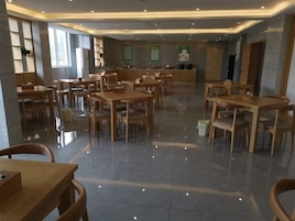Un comedor amplio con mesas y sillas de madera, una barra central y suelo de baldosas.