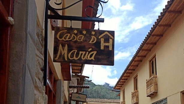 A narrow cobblestone street with a sign for 'Casa de María' hanging from a building. - Casa D Maria (Ollantaytambo)