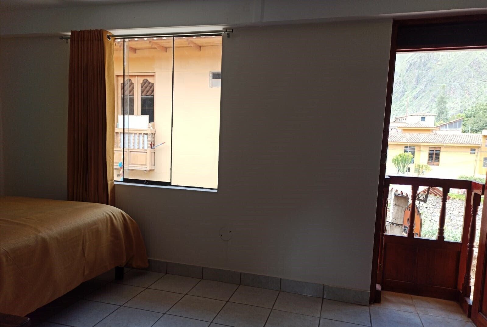 Ein Zimmer mit einem Bett, einem Fenster und Blick auf einen Berg sowie Gebäude.