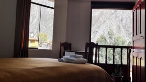 A room with a bed, a chair, a window, and a view of trees. - Casa D Maria (Ollantaytambo)