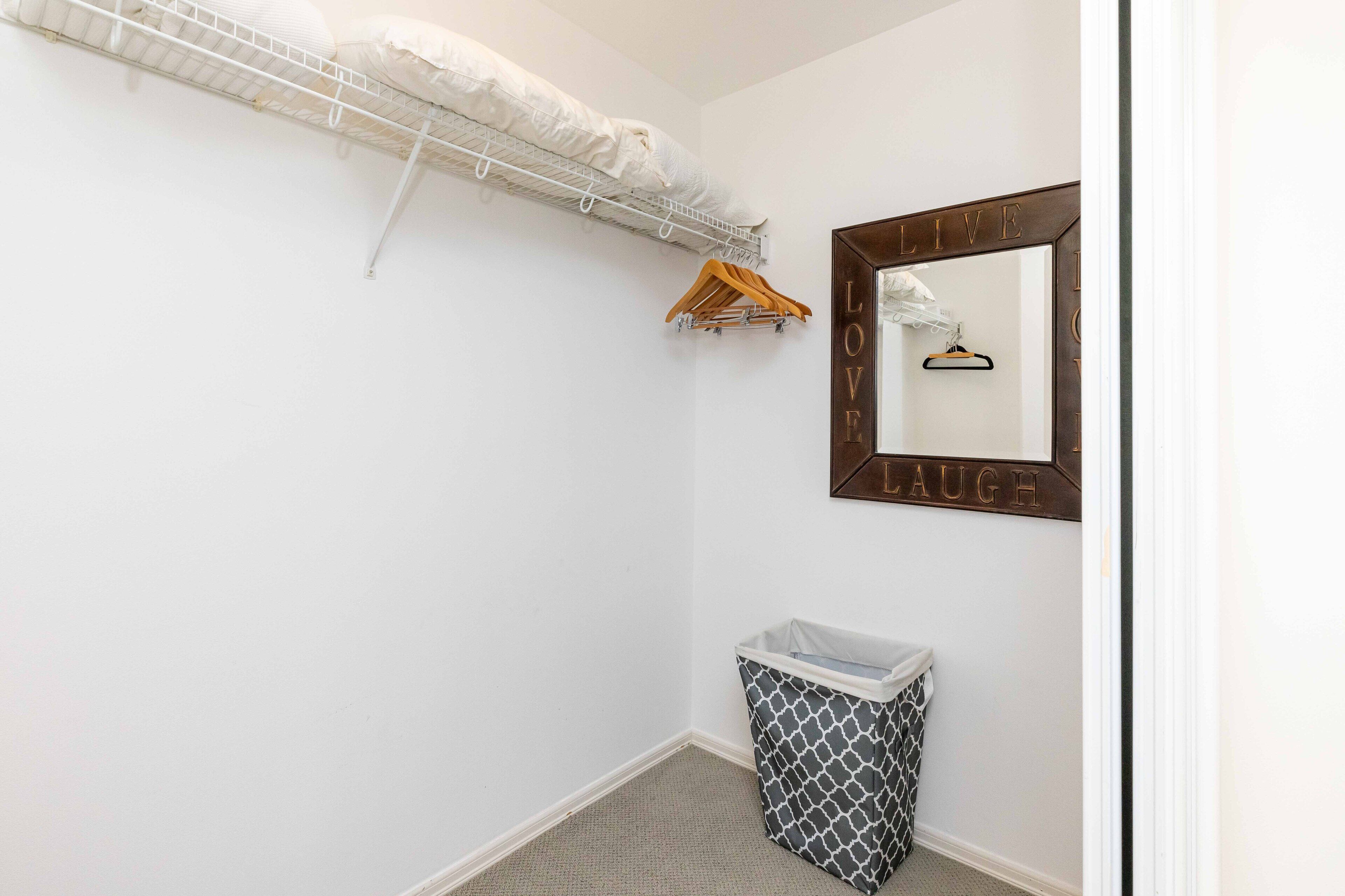 A small, clean bathroom with a white shower, a towel rack, a mirror with 'LIVE LAUGH' framed, and a trash bin.