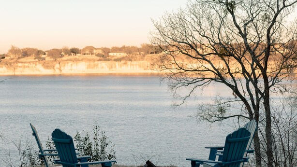 A lakeside patio with two Adirondack chairs and a fire pit. - Whitney Ridge Resort (Clifton)