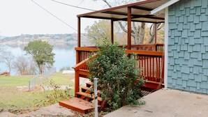 A wooden deck with a metal railing, a small garden area, and a view of a lake. - Whitney Ridge Resort (Clifton)
