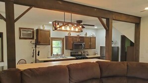 A modern kitchen with wooden beams, a central island, and a hanging light fixture.