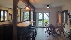 A spacious kitchen with a bar area, wooden chairs, and a dining table.