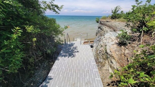 A concrete staircase leading to a beach with a clear view of the ocean.