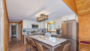 Una cocina moderna con una isla grande, suelo de madera y electrodomésticos de acero inoxidable.