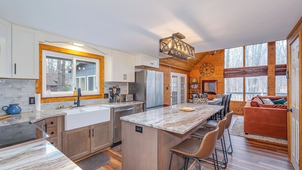 Una cocina moderna con una isla grande, armarios de madera y un comedor con un ventanal amplio.
