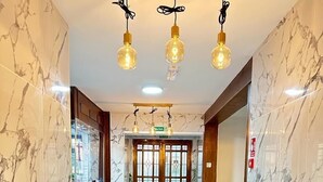 A hallway with marble flooring, a red patterned rug, and a wooden door with glass panels. - Stay Inn Express (Cambridge)