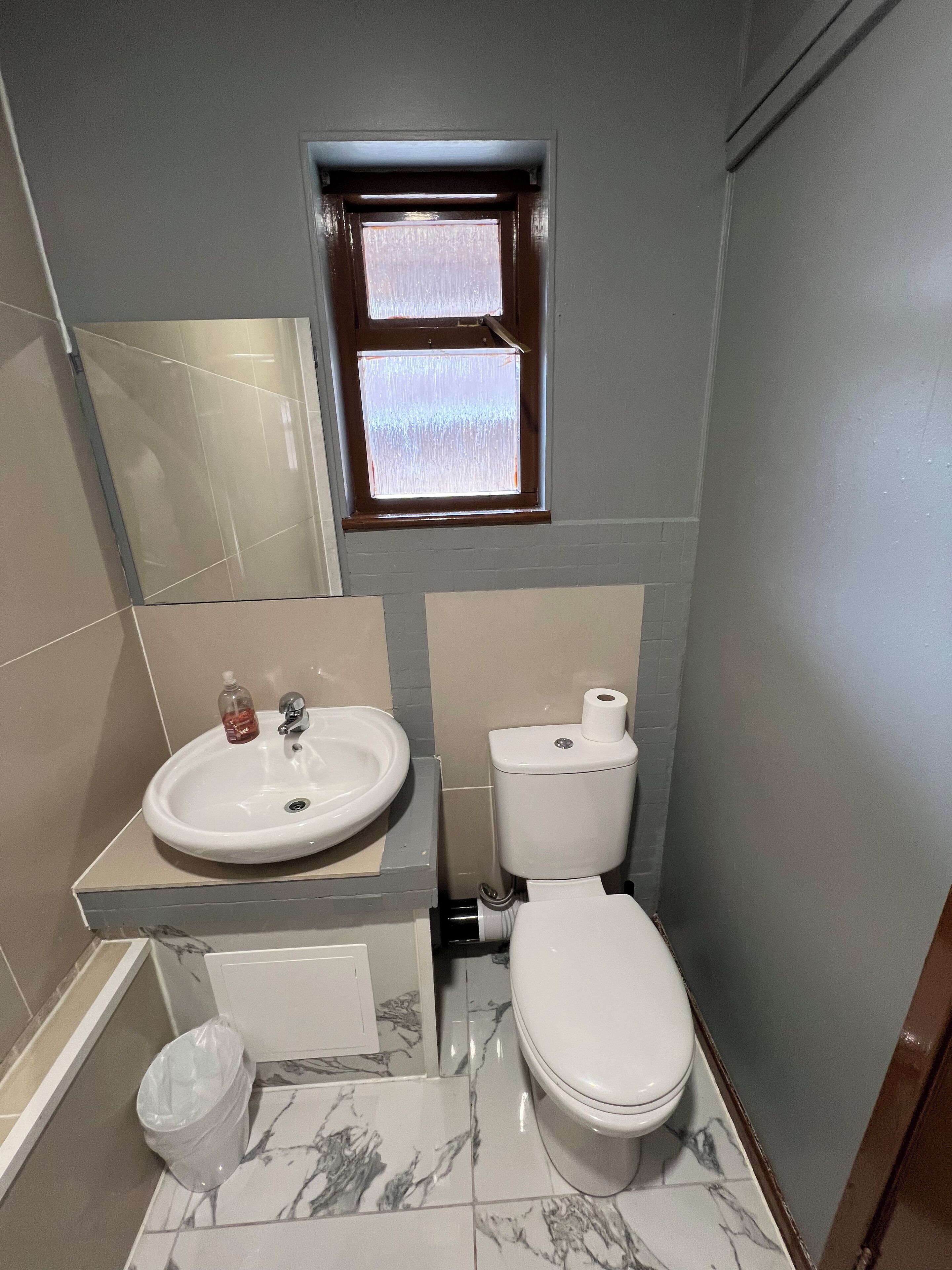 A bathroom with a sink, toilet, and a small window.