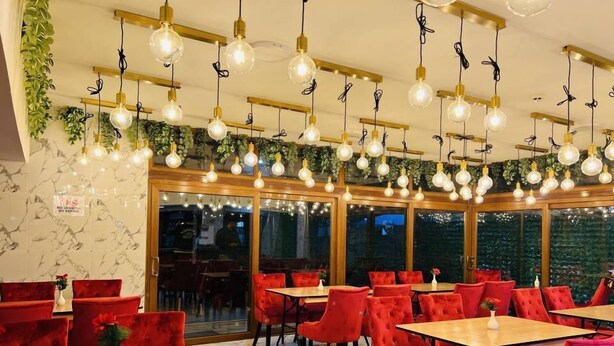 A restaurant with red upholstered chairs, wooden tables, and hanging light fixtures. - Stay Inn Express (Cambridge)