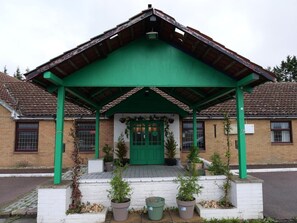 Un bâtiment doté d’un toit végétalisé et d’un auvent d’entrée également végétalisé, entouré de plantes en pot.