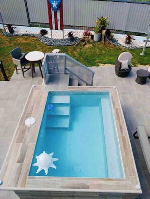 Relax by the pool with a ladder for easy access, surrounded by a deck and lush greenery.