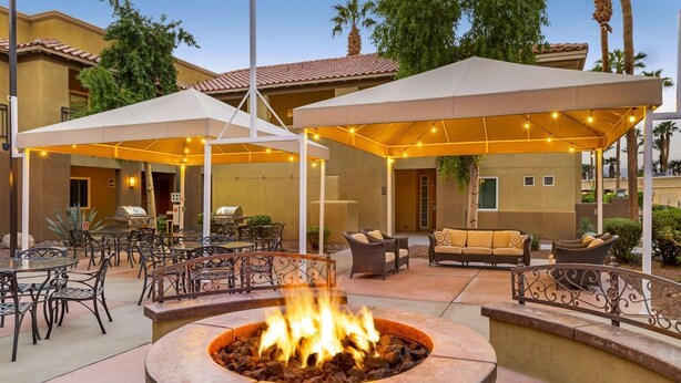 An outdoor patio area with a fire pit, tables, chairs, and umbrellas providing shade. - Marriott Shadow Ridge Village, 1 bedroom. Short Ride to Coachella Music Festival (Palm Desert)
