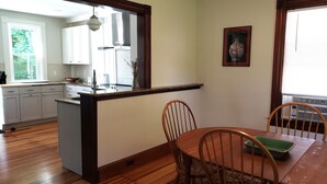 Una cocina con armarios blancos, una isla de madera y un comedor con mesa y sillas.