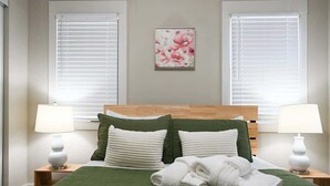 Un lit bien fait, avec une literie verte, des oreillers blancs et une serviette blanche pliée posée sur le lit.