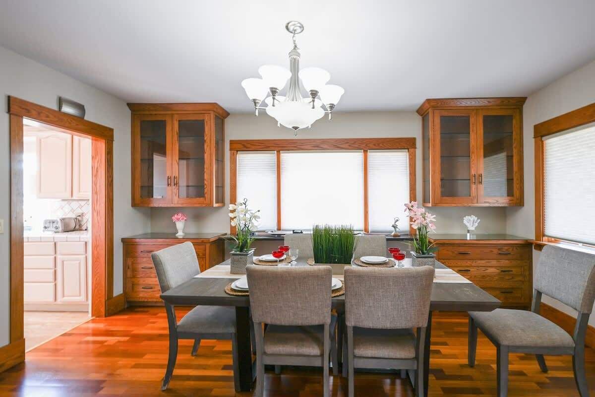 Una cocina moderna con armarios de madera, una mesa de comedor con sillas y una araña.