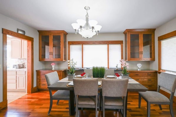 Una cocina moderna con armarios de madera, una mesa de comedor con sillas y una araña.