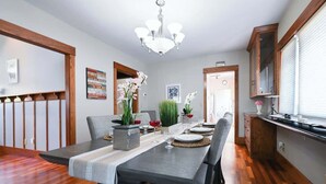 Un espace repas comprenant une longue table, des chaises, un lustre et un plancher en bois.