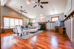 A spacious living room with hardwood flooring, a fireplace, ceiling fans, and a television. - Spacious Central San Jose SFH 3BR w/crib Free park (San Jose)