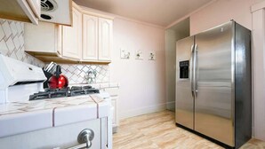 Une cuisine avec un fourneau blanc, un réfrigérateur en acier inoxydable et des armoires de couleur claire.