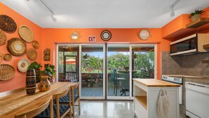 A bright orange interior with a dining area, kitchen, and sliding glass doors leading to a garden.