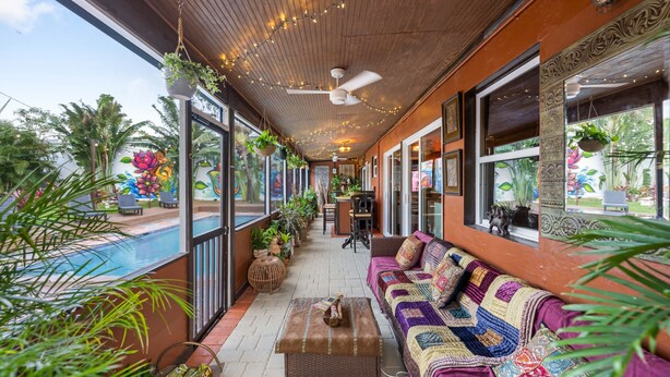 A covered outdoor area with a pool, seating, and potted plants.