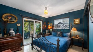 A bedroom with a bed, dresser, and a window with a view.