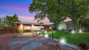 A house with a stone pathway leading to the front door, surrounded by a well-maintained lawn and a wooden fence.