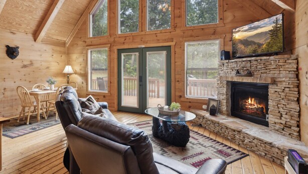 Ein gemütliches Blockhaus-Interieur mit Kamin aus Naturstein, einer Ledersofa und einem Essbereich.