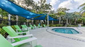 A poolside area with green lounge chairs, a pool, and a blue canopy. - NICE 15BR Home Near Disney | Groups Welcome (Kissimmee)