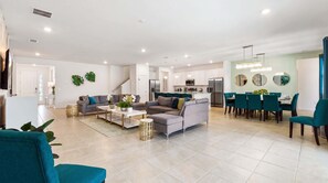 A spacious living area with a sofa, coffee table, and dining table set up.