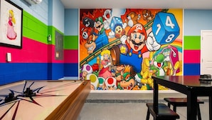 A colorful room with a mural of various video game characters, a pool table, and a dartboard. - NICE 15BR Home Near Disney | Groups Welcome (Kissimmee)