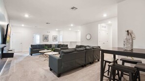 Ein modernes Wohnzimmer mit einer Eckcouch, einem runden Couchtisch und einem Essbereich mit einer Bank.