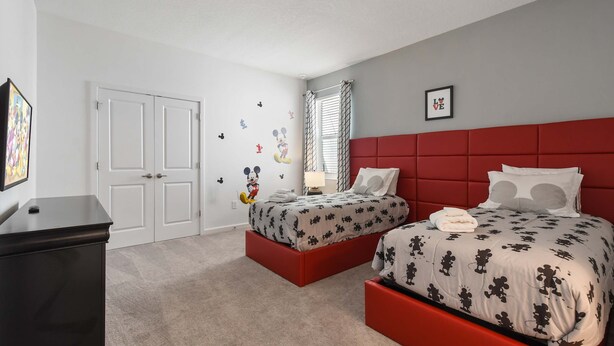 A bedroom with two beds, a red headboard, and Mickey Mouse decals on the walls. - NICE 15BR Home Near Disney | Groups Welcome (Kissimmee)