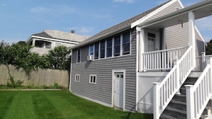 A two-story house with a covered porch and a staircase leading to the second floor. - Cottage | 3 Min Walk to the Beach (Yarmouth)