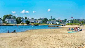A beach with houses along the shore, a sandy beach, and a calm body of water. - Cottage | 3 Min Walk to the Beach (Yarmouth)
