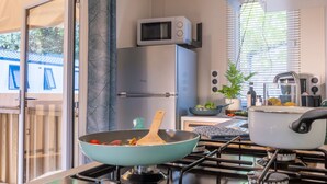 Une cuisine moderne équipée d’un four à micro-ondes, d’un réfrigérateur, d’une cuisinière et d’une fenêtre avec des stores.