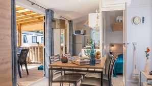 Un espace de vie compact comprenant un coin repas, une kitchenette et une petite chambre.
