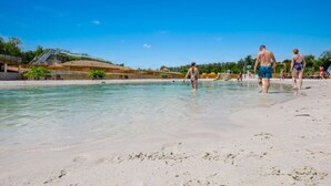 Une plage à l’eau claire, avec un toboggan aquatique et un rivage sablonneux.