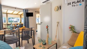 Un soggiorno moderno con zona pranzo, TV a parete e un cartello con la scritta "ZE PLACE To be".
