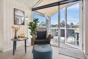 Un salon moderne doté d’une grande porte-fenêtre coulissante donnant sur une terrasse extérieure.